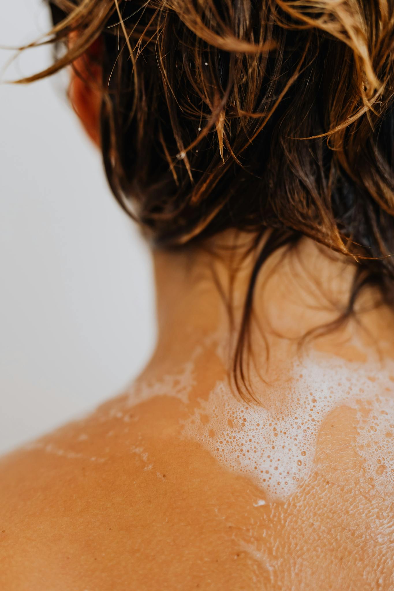 Detailed shot of wet hair with soapy water on a back, highlighting cleansing routine.